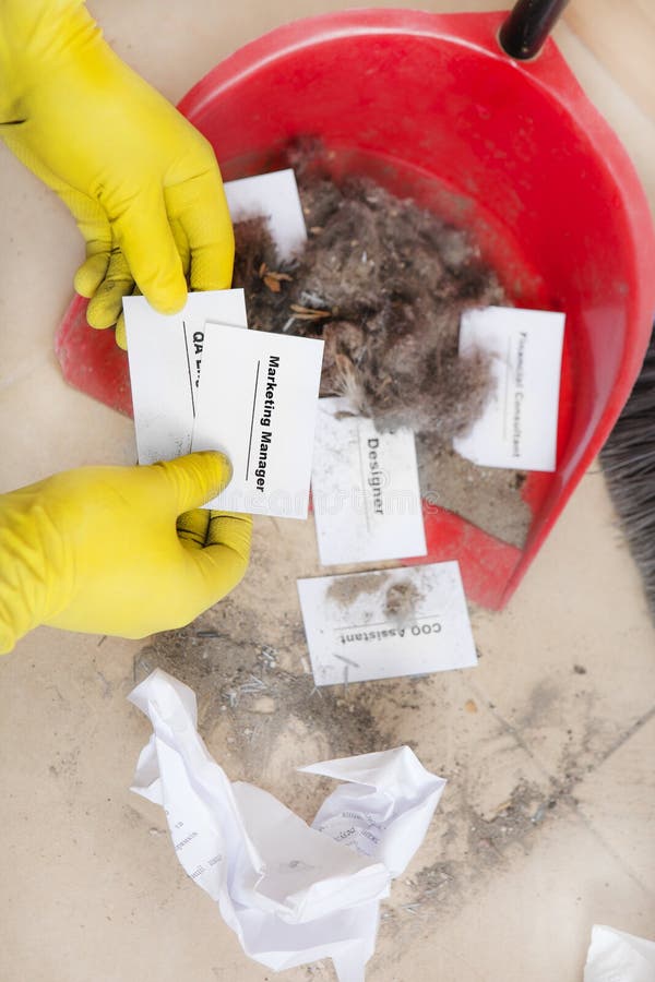 Staff reduction concept - Cutting staff and employee Job Reduction. Dismissal. Office cleaner throw in the debris staff business cards. Crisis management and royalty free stock photo